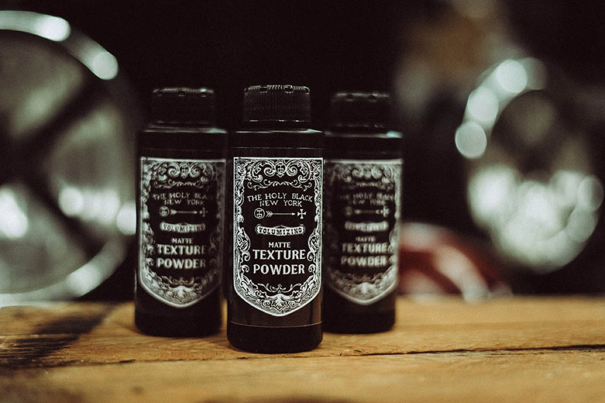 Three Holy Black Texture Powder bottles on wooden surface